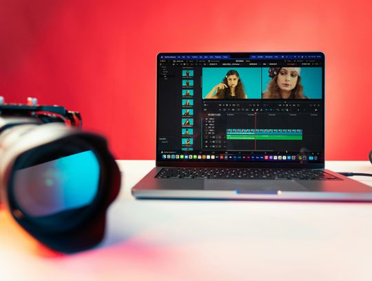 laptop and camera sitting on a desk with video editor