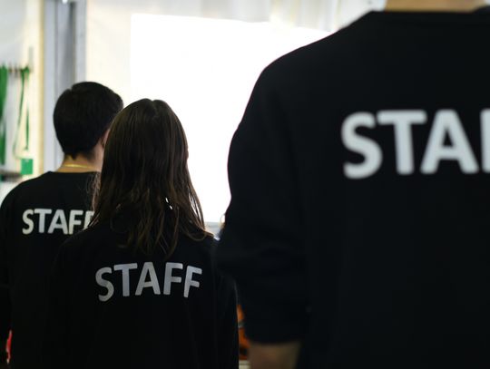 group of people in black staff shirts standing in a room