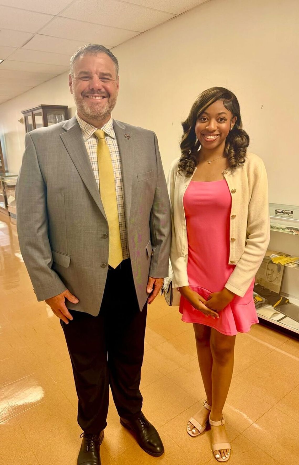 Canton High senior begins second term on state student advisory council A smiling man in a gray jacket and yellow tie stands beside a smiling young woman in a pink top