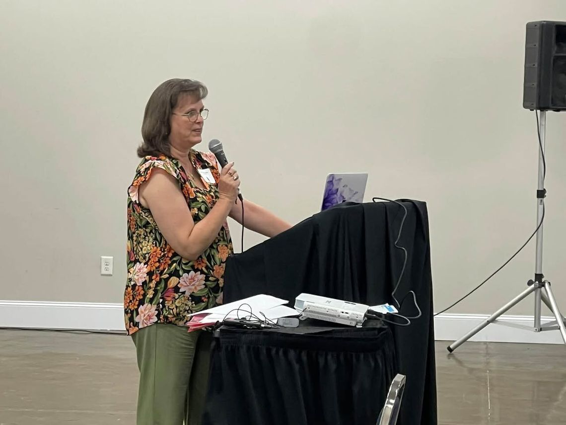 A woman speaks into a microphone at a podium during a conference session