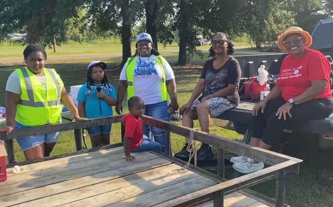 Continue to Keep Canton Beautiful Two children and three women in safety vests sit and stand around a flatbed trailer in a park