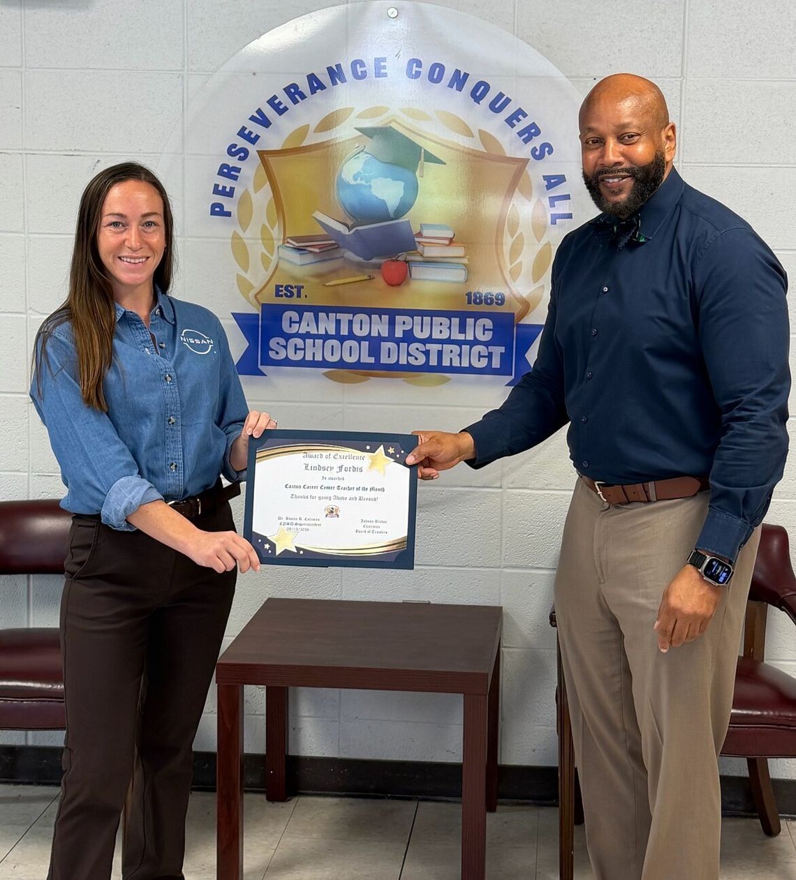 Fordis named Canton Career Center Teacher of the Month A woman and a man hold a framed certificate together in front of a Canton Public School District banner