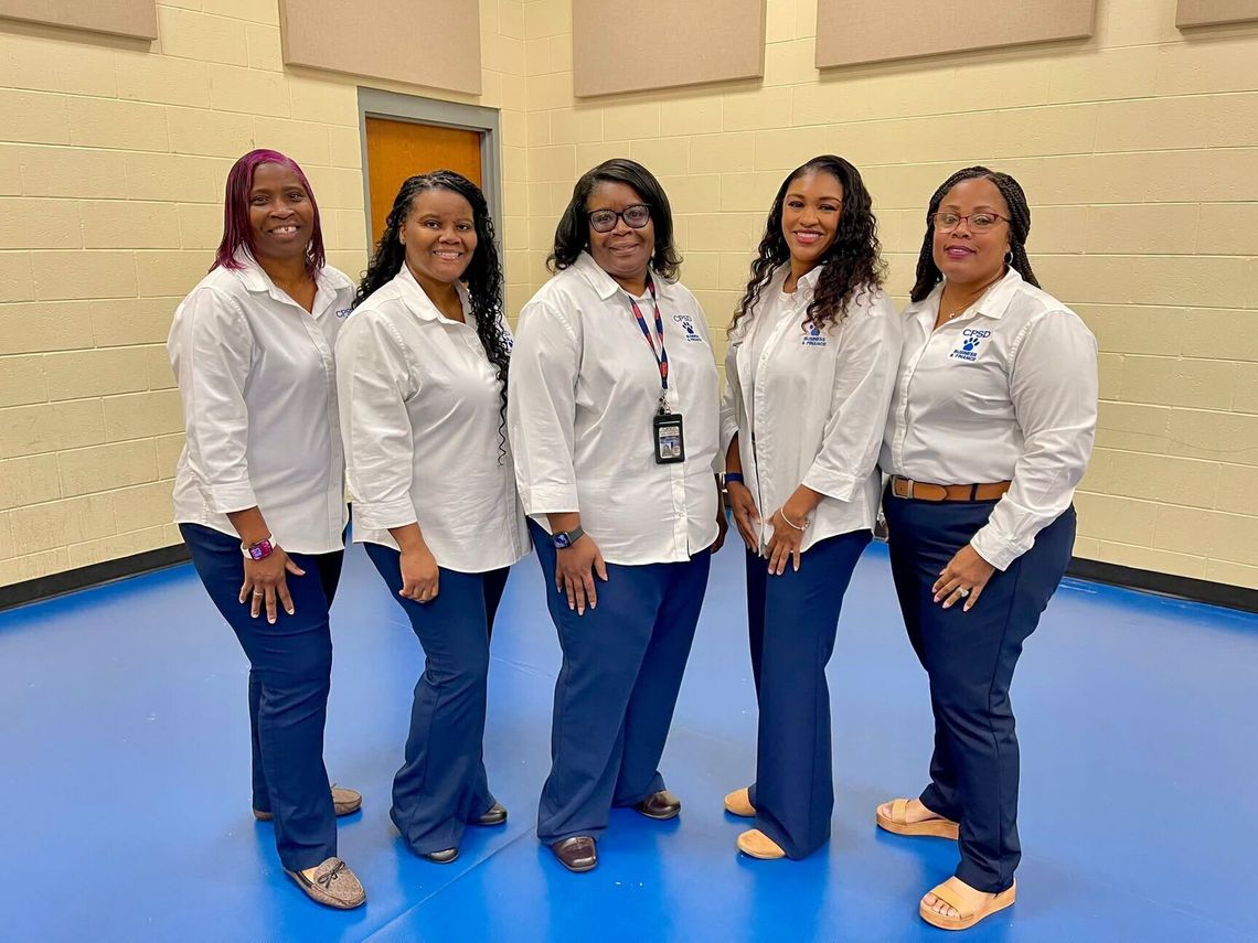 The Business Office holds annual procedural training Five women in matching white shirts and navy pants stand together in a gym