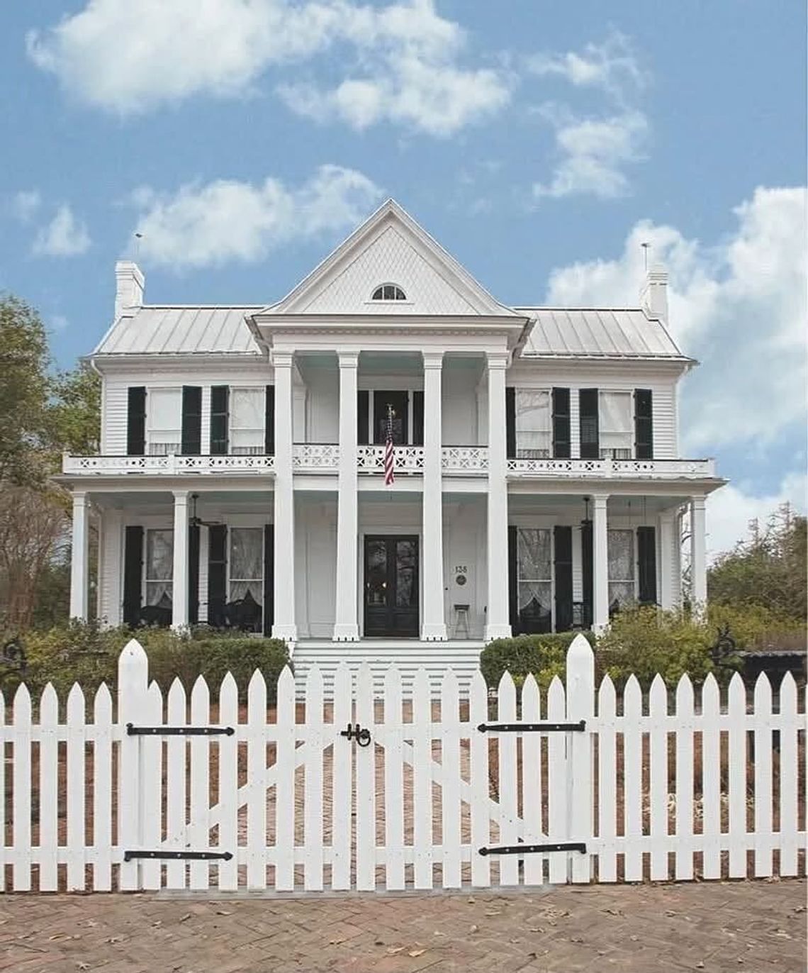 This Old House: The Priestley Home ca. 1852 A white two-story antebellum house with tall columns and a white picket fence under a blue sky