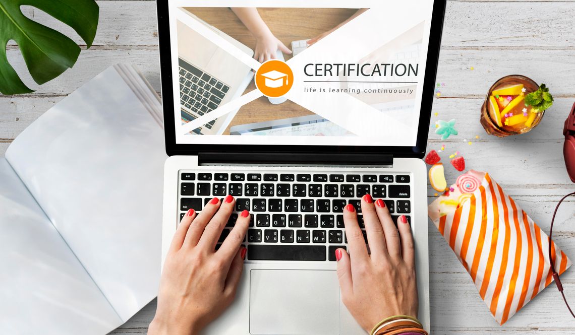 Top HR Certifications for Career Growth female with red nails using laptop with certifcation on the screen and snacks on table